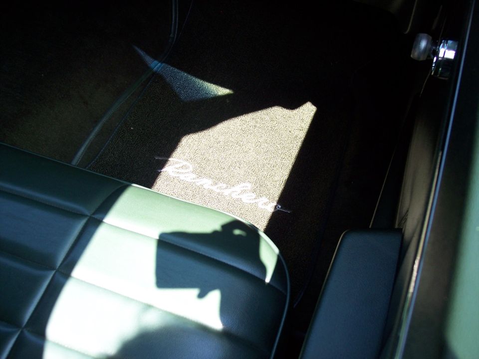 Green interior floor mat with embroidered 'Ranchero' text, illuminated by sunlight