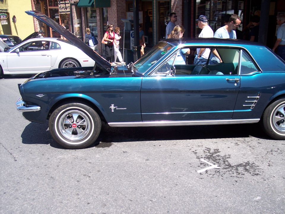 1965 Ford Mustang coupe, teal paint, hood open. White Ford Mustang in background