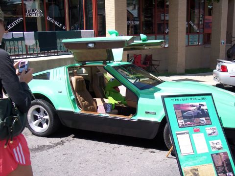 1972 Ford Ranchero - A unique green sports car with gullwing doors open, a Kermit the Frog plush toy and an informational display board.