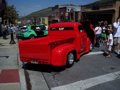 1972 Ford Ranchero - A bright red pickup truck is parked on a street with people gathered around.