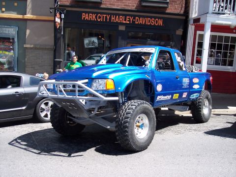 1972 Ford Ranchero - Modified blue Ford Ranger pickup truck with off-road tires and roll cage parked on street.