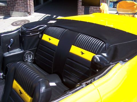 1972 Ford Ranchero - The interior of a yellow convertible shows black seats with yellow accents and horse emblems.