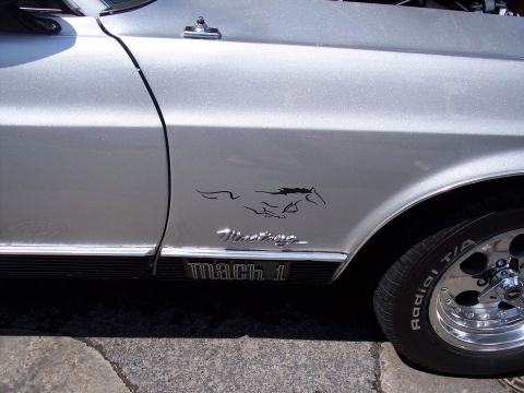 1972 Ford Ranchero - Close-up of a silver car's fender, a running horse emblem and a 'Mach 1' badge.