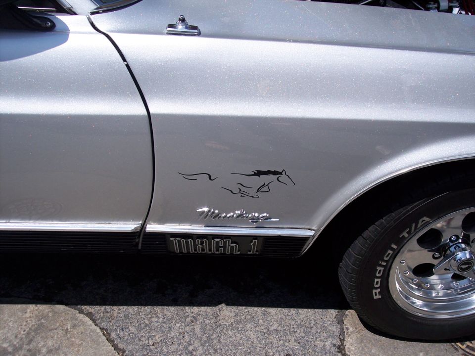 Silver car fender with running horse emblem and Mach 1 badge
