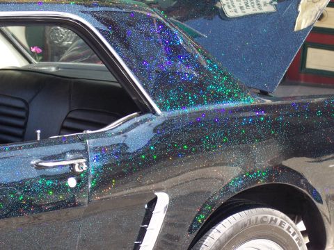 1972 Ford Ranchero - A custom black car with multi-colored glitter paint is shown from the side, with its trunk open.