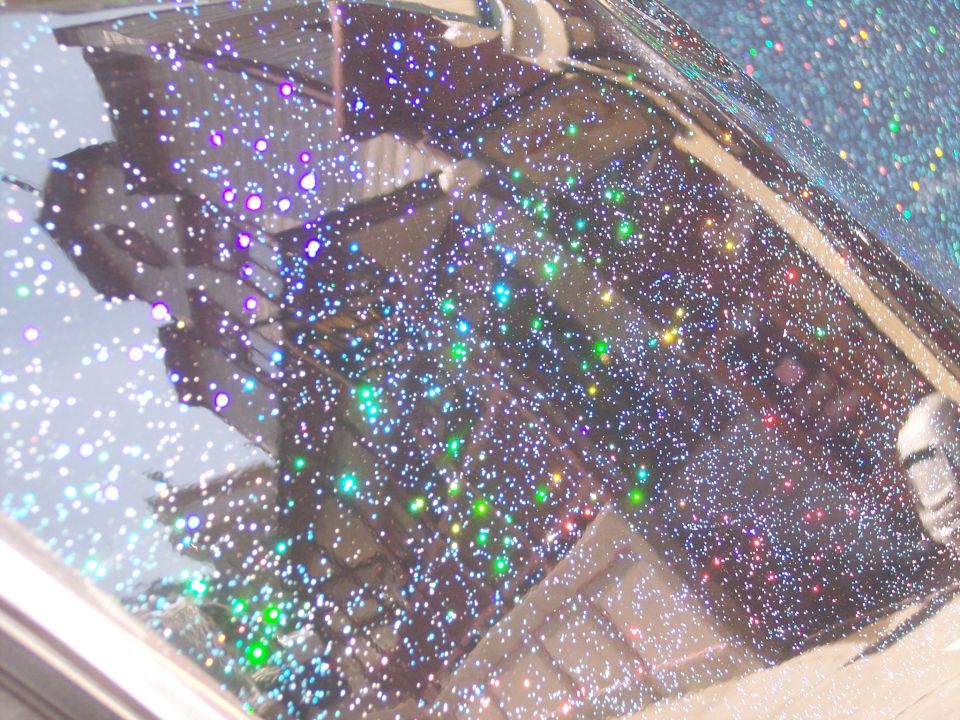 Close-up of a car roof with a dark base coat covered in multi-colored glitter
