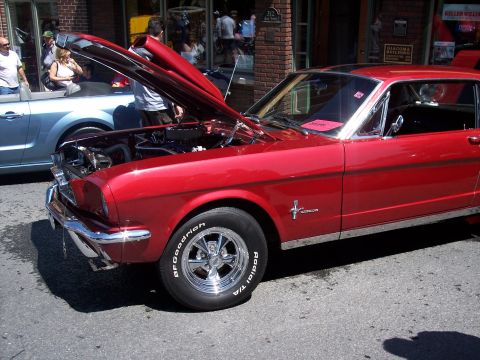 1972 Ford Ranchero - A shiny red coupe with its hood up is displayed on a sunny day, with another car parked nearby.