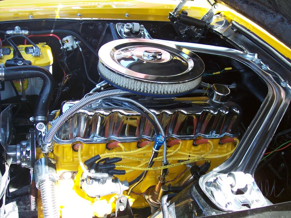 Yellow engine block with chrome valve covers and air cleaner. Yellow spark plug wires are visible