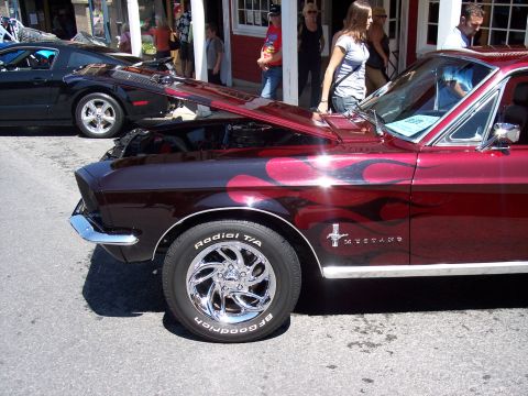1972 Ford Ranchero - A classic Mustang with custom flame paint and chrome wheels is displayed with its hood open.