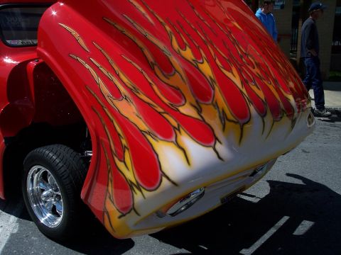 1972 Ford Ranchero - A red pickup truck hood with custom flame graphics is open, revealing a chrome wheel.