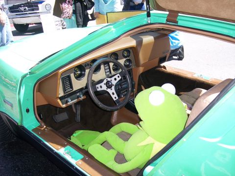 1972 Ford Ranchero - A plush Kermit the Frog sits in the passenger seat of a green car, with another vehicle visible in the background.