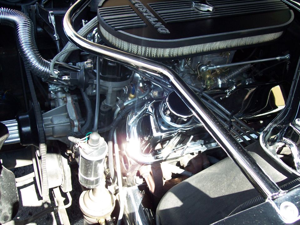 Engine bay showing air cleaner with "MUSTANG" text, chrome strut bar, distributor, and carburetor