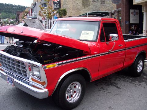 1972 Ford Ranchero - A bright red pickup truck is parked with its hood open, revealing the engine. The Ford emblem is visible on the front grille.