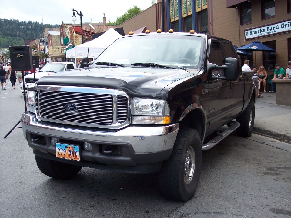 Black Ford F-Series truck parked on street, O'Shucks Bar & Grill in background