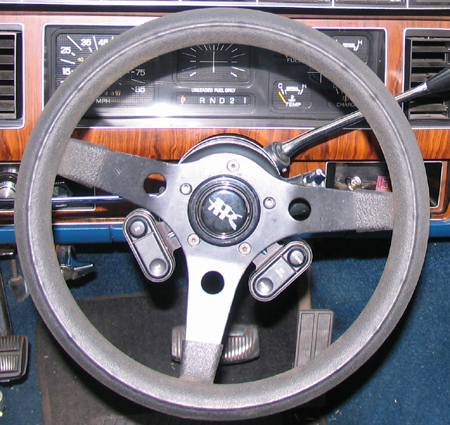 1984 Ford Bronco - Aftermarket steering wheel with 'TRK' logo is installed in a vehicle with wood grain trim and visible gauges.