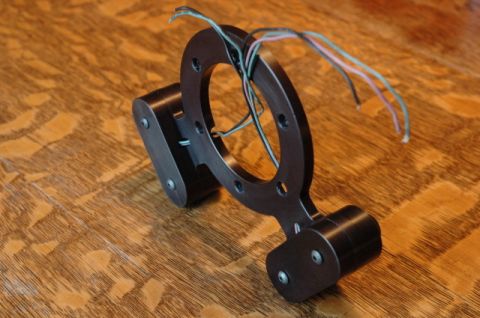 1984 Ford Bronco - Aftermarket steering wheel hub adapter with wires shown on a wooden background.