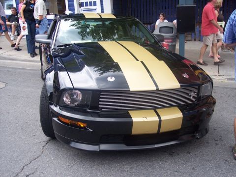 1972 Ford Ranchero - Front view of a black Ford Mustang with gold stripes parked on a street.