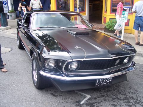 1972 Ford Ranchero - A black 1969 Ford Mustang Mach 1 is parked on a street in front of shops.