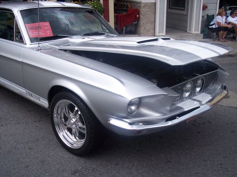 1972 Ford Ranchero - A silver 1968 Ford Mustang GT500 with racing stripes and its hood open is parked on a street.