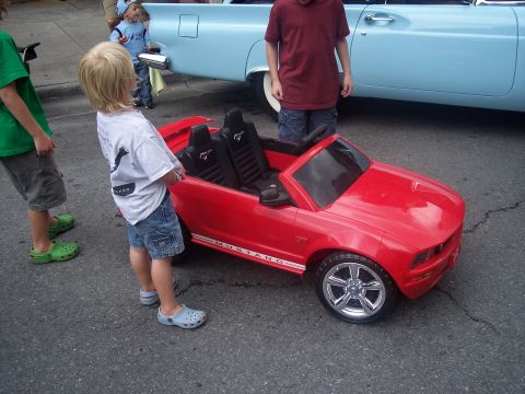 1972 Ford Ranchero - A red toy Mustang convertible sits on asphalt next to a blue classic car.
