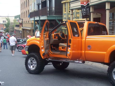 1972 Ford Ranchero - An orange pickup truck is parked on a street with its doors open, revealing the interior and custom wheels.