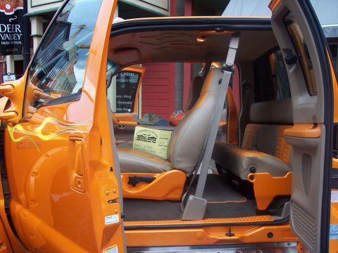 1972 Ford Ranchero - Custom orange pickup truck interior with flame graphics and tan seats. Sign on passenger seat.