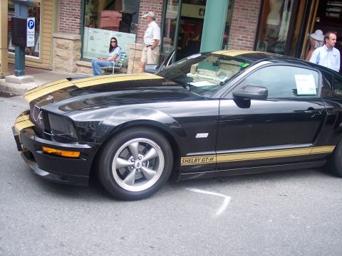 1972 Ford Ranchero - A black Ford Mustang Shelby GT-H with gold racing stripes is parked on a street.