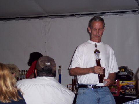 1972 Ford Ranchero - A man receives a trophy at what appears to be an awards ceremony or car show event.