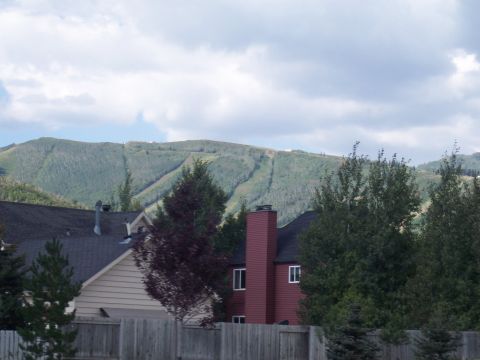 1972 Ford Ranchero - A mountain landscape with houses and trees in the foreground under a cloudy sky.