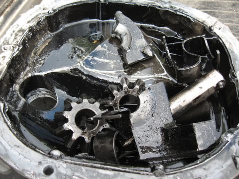 1994 Ford Bronco - The internal components of a differential housing are shown, heavily damaged and submerged in oil.