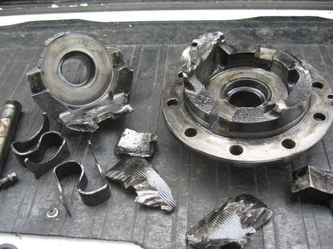 1994 Ford Bronco - Damaged differential components lie scattered on a textured surface, indicating severe mechanical failure.