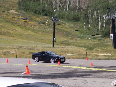 1972 Ford Ranchero - A black Ford Mustang is driven on a course marked by cones and tape, with a ski lift visible on the hill behind it.