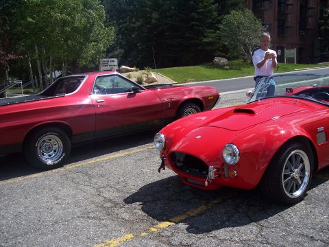 1972 Ford Ranchero - Two classic red vehicles are parked side-by-side, with a man standing behind them.