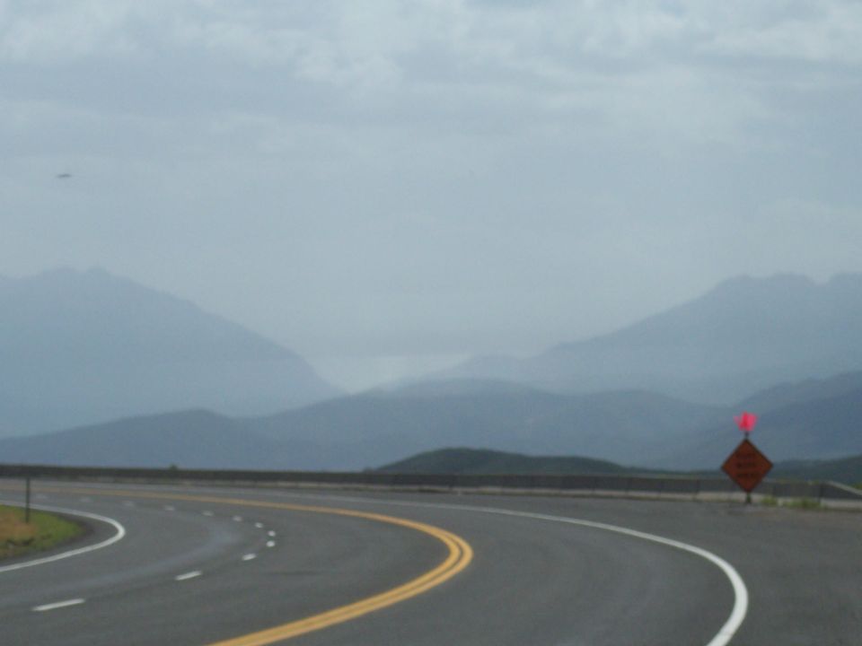 Curving highway with layered mountains under a cloudy sky
