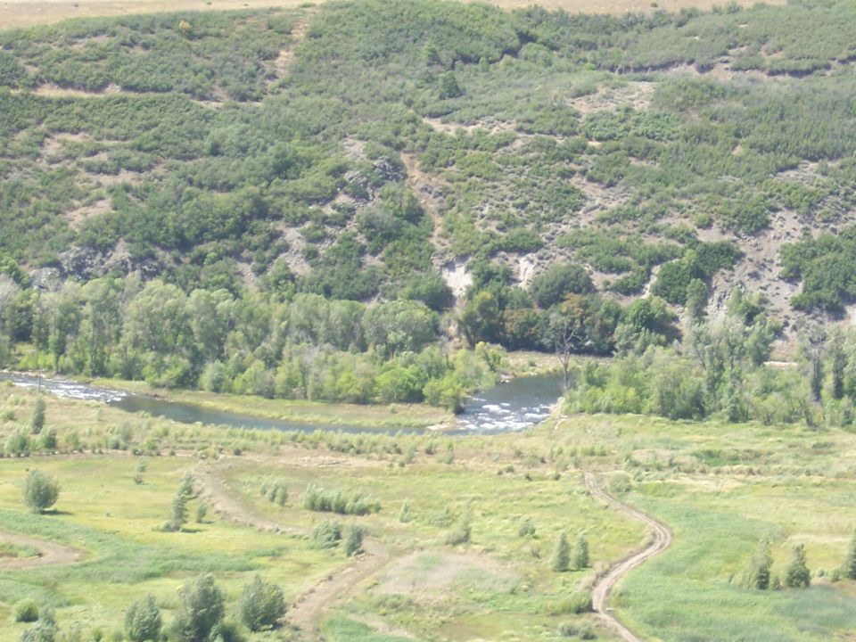 River flowing through a valley with green hills and dirt paths