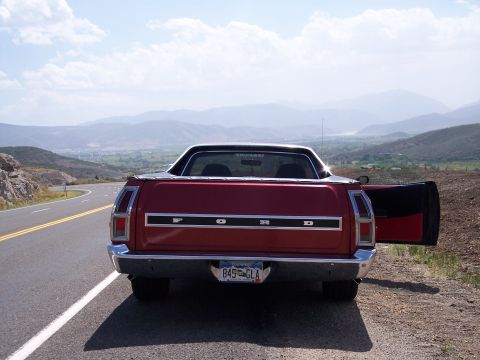 1972 Ford Ranchero - A red 1972 Ford Ranchero is parked on the side of a road with a scenic mountain view in the background.