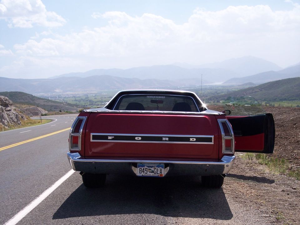 Red 1972 Ford Ranchero parked on roadside, rear view, driver door open