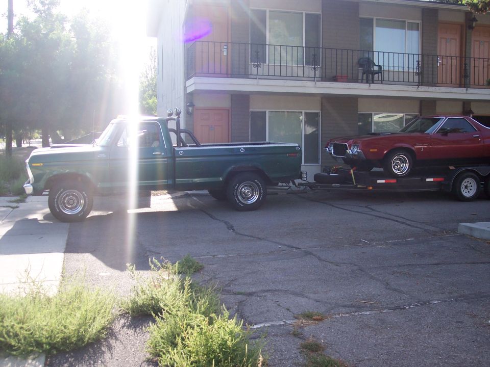 Red 1972 Ford Ranchero on trailer towed by green pickup