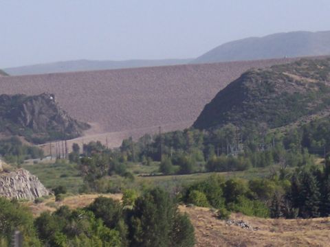 1972 Ford Ranchero - A vast dam dominates the landscape, with rolling hills and trees in the foreground under a hazy sky.