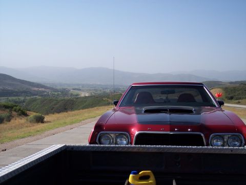 1972 Ford Ranchero - A red coupe with a black hood scoop is parked on a scenic overlook, with a valley in the background.