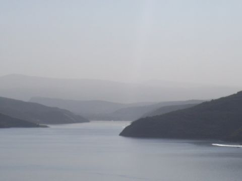 1972 Ford Ranchero - A , hazy view of hills meeting a calm body of water under a pale sky.