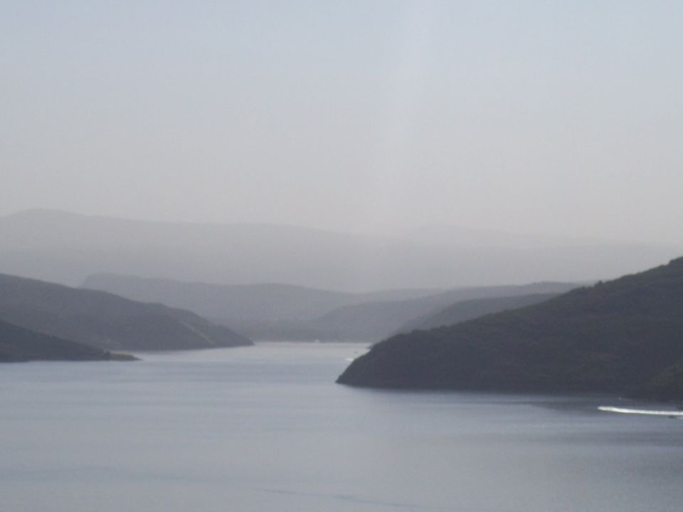 Misty landscape with rolling hills and a body of water