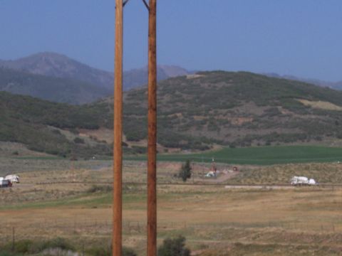 1972 Ford Ranchero - A wide shot of a rural landscape rolling hills, power poles, and two trucks on a distant road.