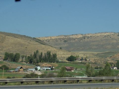 1972 Ford Ranchero - A scenic view of a rural valley farmhouses, trees, and rolling hills under a bright blue sky.