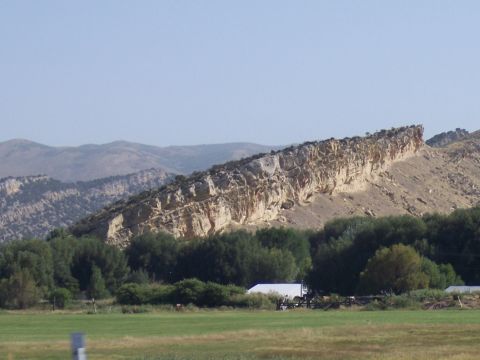 1972 Ford Ranchero - A wide landscape shot shows a prominent rock ridge with trees and a building in the foreground under a clear sky.