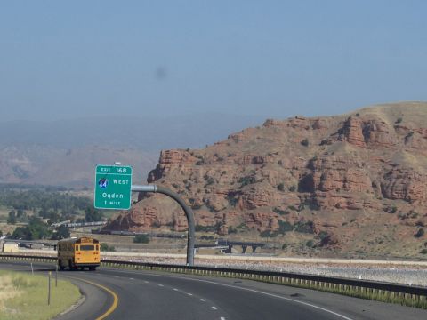 1972 Ford Ranchero - A yellow school bus travels down a highway near red rock formations, with an exit sign for Ogden visible.