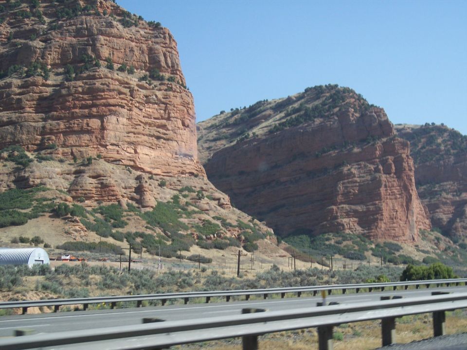 Red rock canyon landscape with a highway in the foreground and a building in the distance