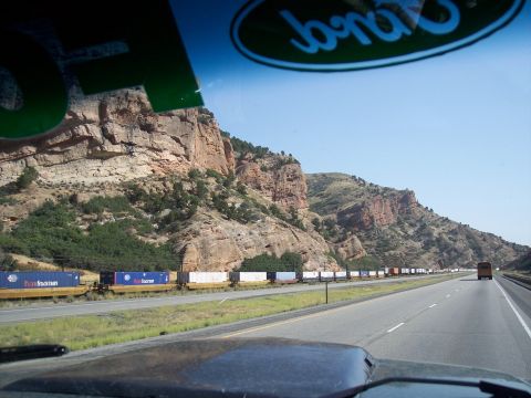 1972 Ford Ranchero - A highway stretches through a mountainous landscape with a long train running alongside.