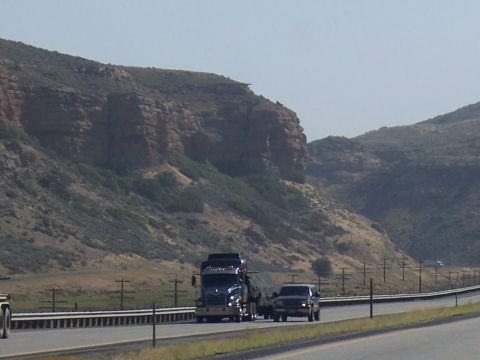 1972 Ford Ranchero - A semi-truck and an SUV travel down a highway with a mountainous landscape.