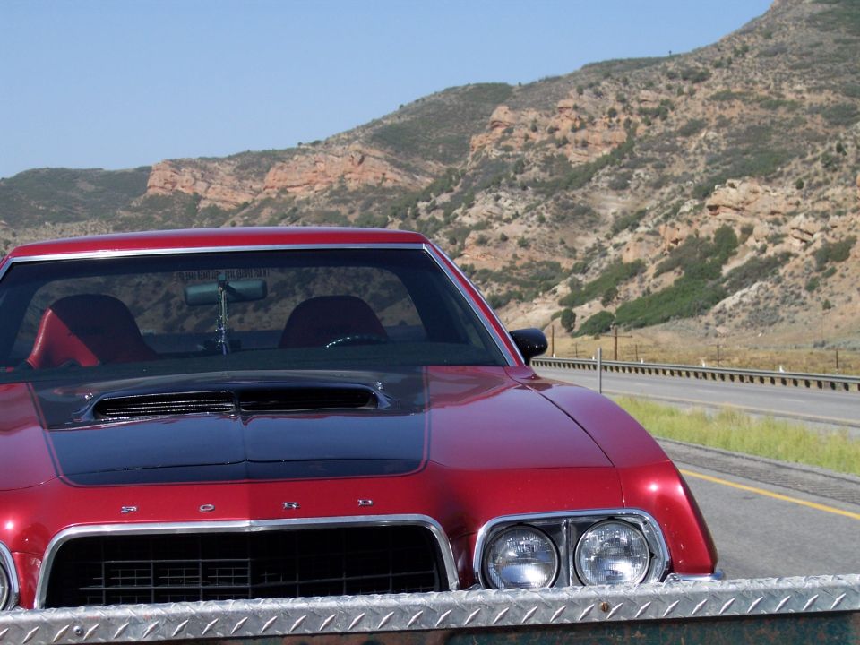 Red 1972 Ford Ranchero front view with black hood scoop and diamond plate bumper